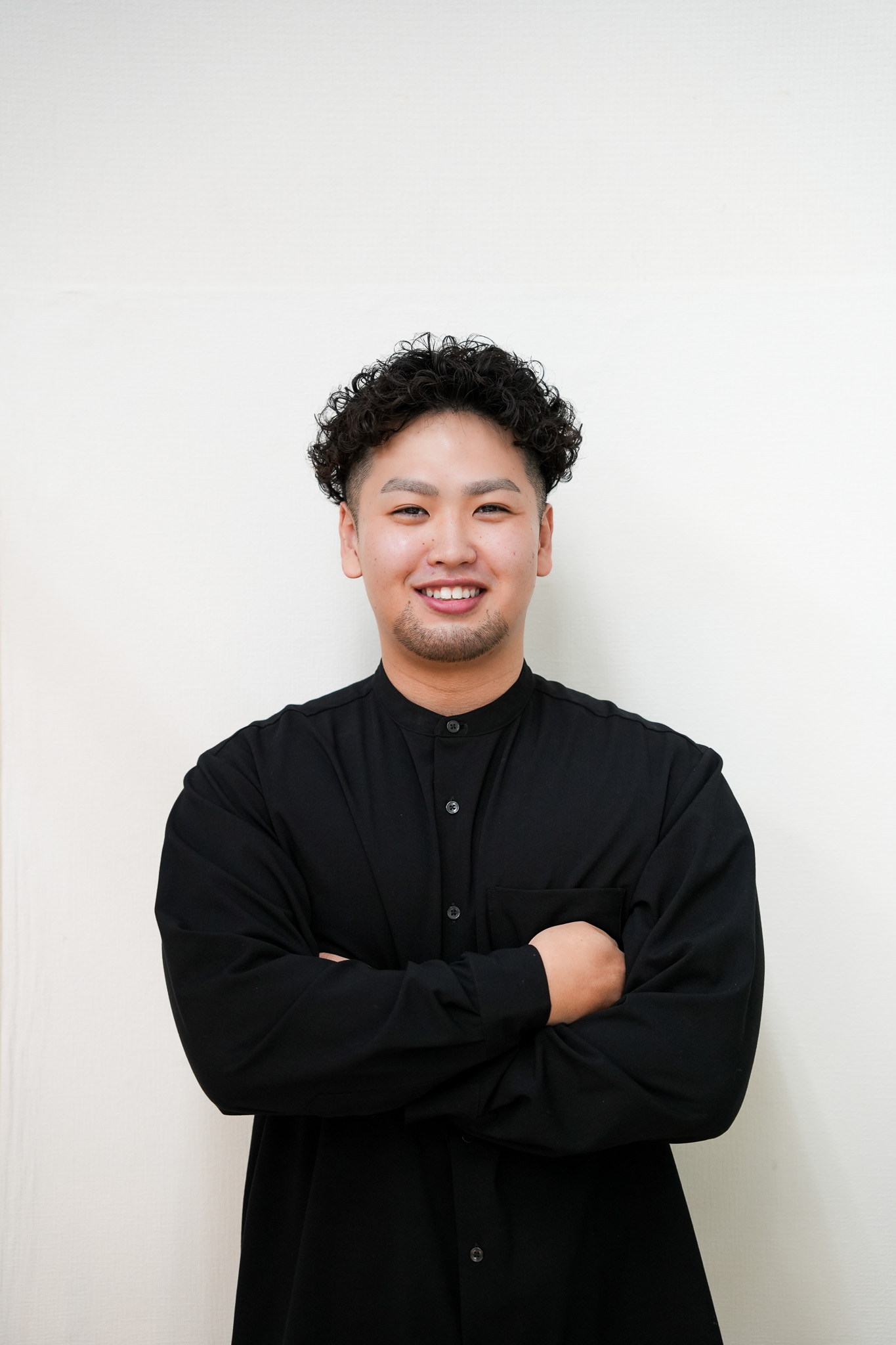 黒い施術着で笑顔を見せる、柔道整復師の亀﨑奏汰